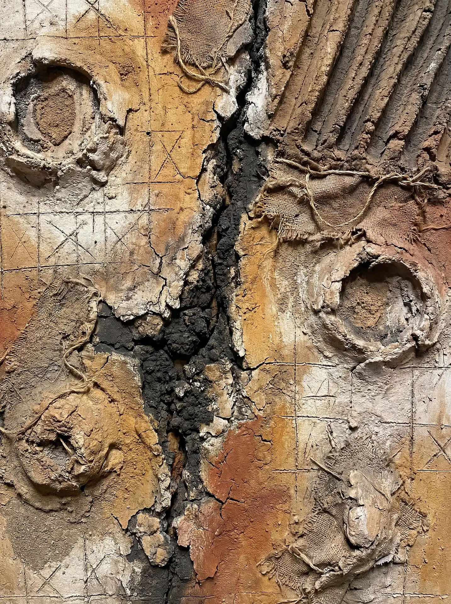 A layered arrangement of coarse burlap and sculpted plaster is split by a deep vertical fissure. This mixed media piece uses a warm palette of ochre and terracotta to create a rustic, weathered texture reminiscent of ancient archaeological finds or dry, cracked earth. Artwork by Constantine Cheshire
