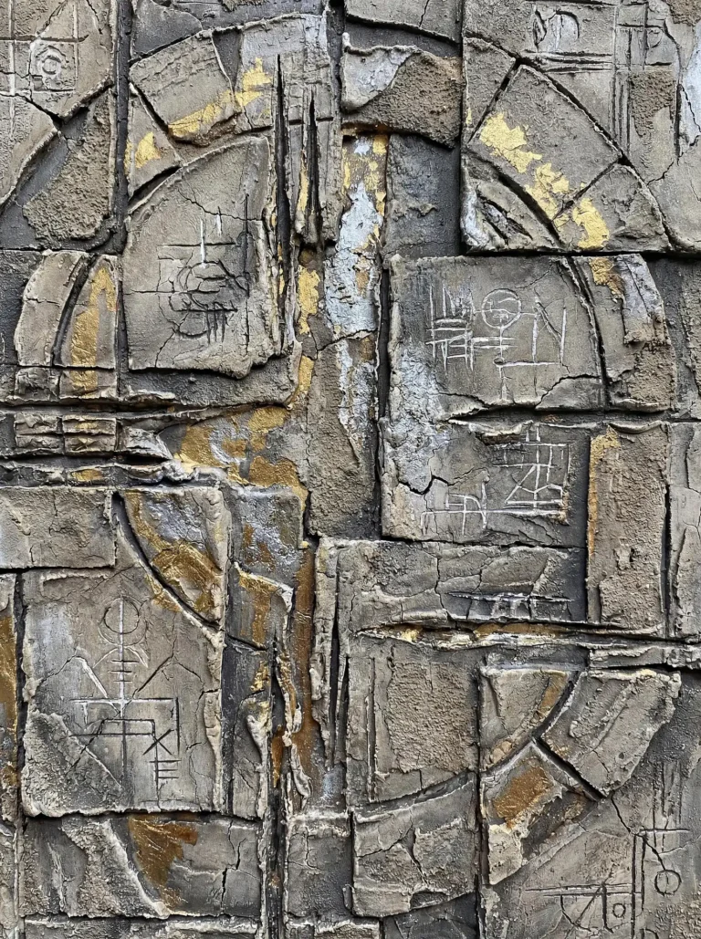 Mysterious and ancient-looking, this grey concrete relief features deep-set cracks, metallic gold highlights, and etched geometric sigils. The mixed-media artwork combines brutalist industrial textures with gold leaf to create a complex, weathered architectural surface. Artwork by Constantine Cheshire