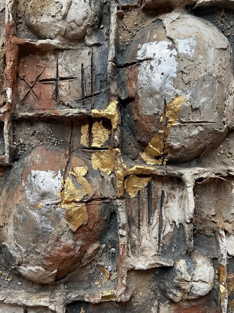 Weathered clay, burlap, and rough cement provide a tactile foundation for shimmering gold and silver leaf accents. This abstract composition features carved markings and rounded geometric forms that evoke the feeling of an industrial archaeological find. Artwork by Constantine Cheshire