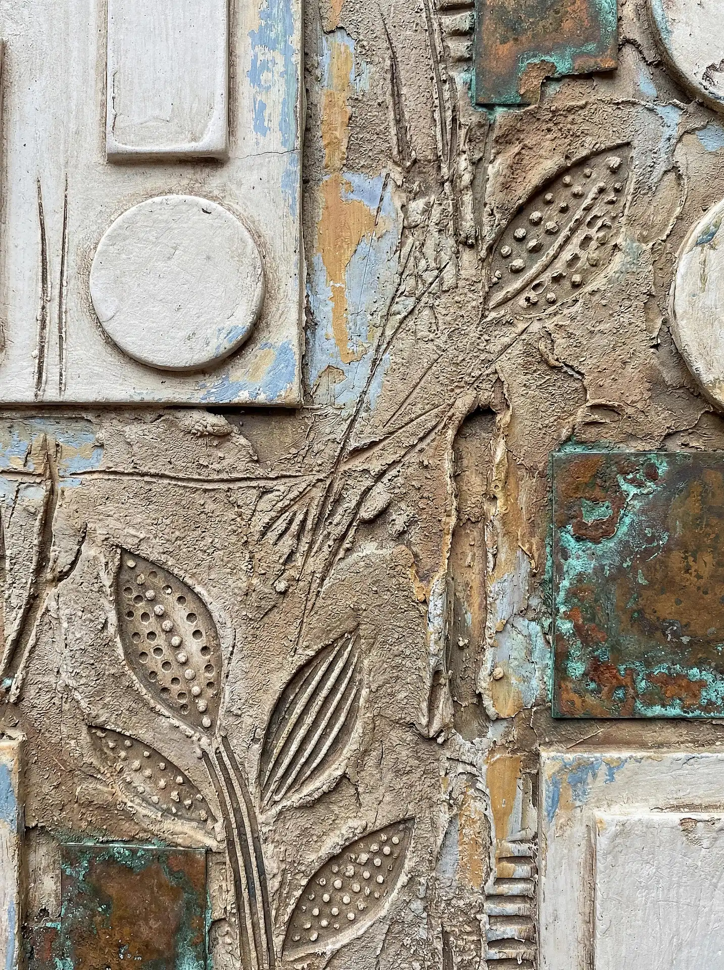 An atmosphere of weathered elegance defines this textured relief featuring botanical leaf imprints and oxidized copper plates. The composition blends earthy sand tones with pops of verdigris and faded blue, creating a rustic yet sophisticated piece of wall art. Artwork by Constantine Cheshire