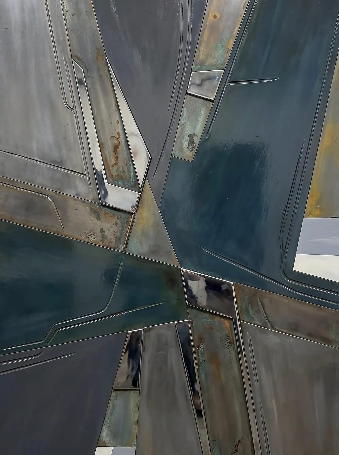 Muted teal and grey tones define these intersecting geometric panels, creating a moody industrial abstract artwork. This piece features a weathered metallic texture with rusted accents and sharp angular lines for a futuristic, mechanical feel. Artwork by Constantine Cheshire