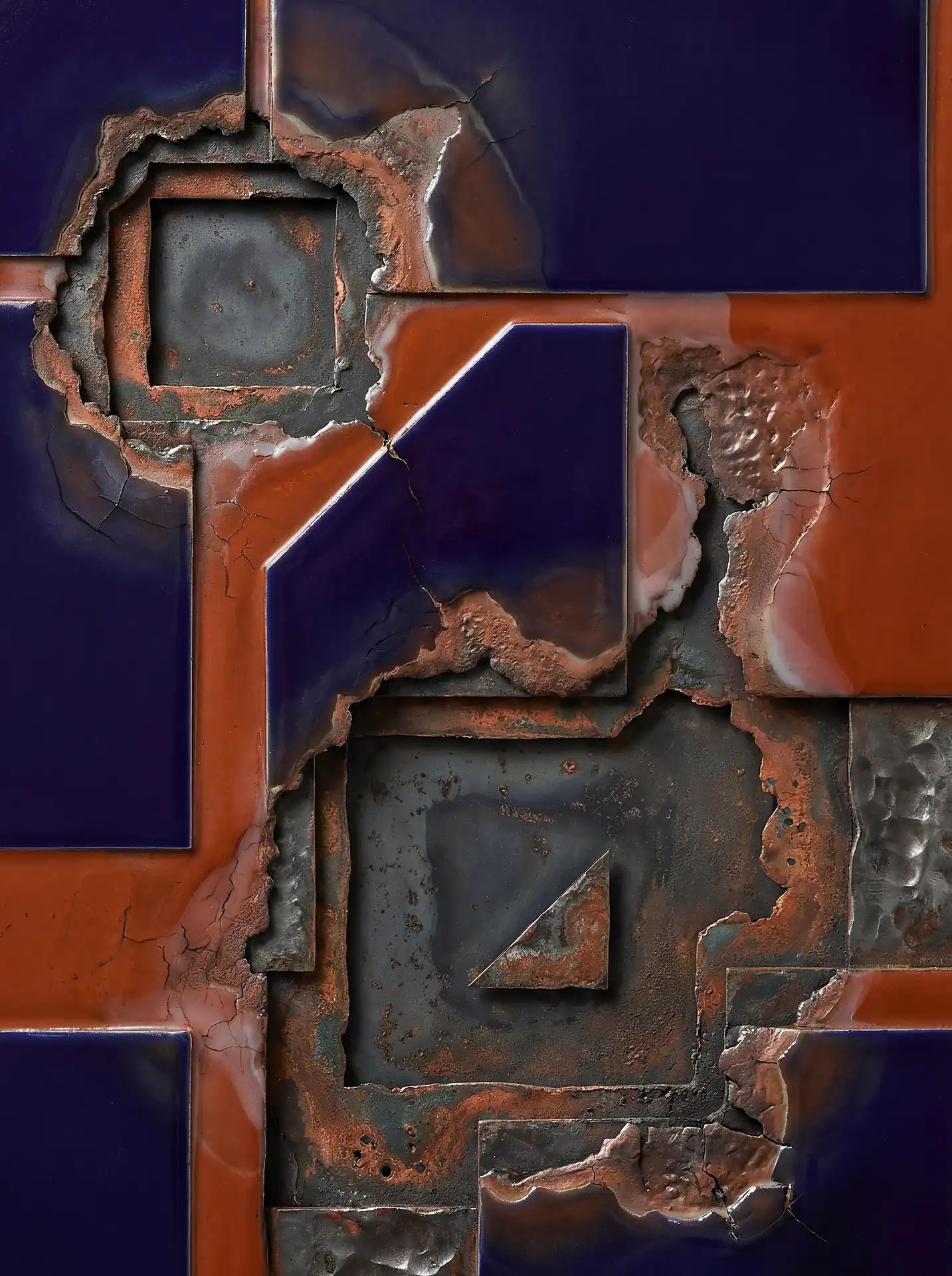 Glazed ceramic and corroded metal textures combine in this sophisticated abstract relief featuring deep indigo and burnt orange tones. The geometric composition showcases a study in decay and structure through shattered tiles and pitted surfaces. Artwork by Constantine Cheshire