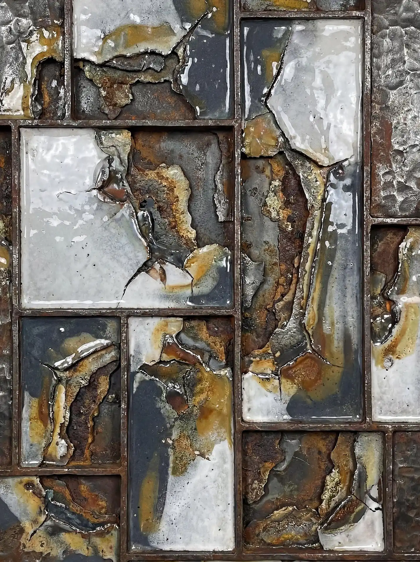 A staggered grid arrangement of rectangular metal frames displays heavily weathered and cracked enamel surfaces. This industrial abstract piece showcases a palette of rusty orange, cool grey, and stark white with rich textures of oxidation and peeling glaze. Artwork by Constantine Cheshire