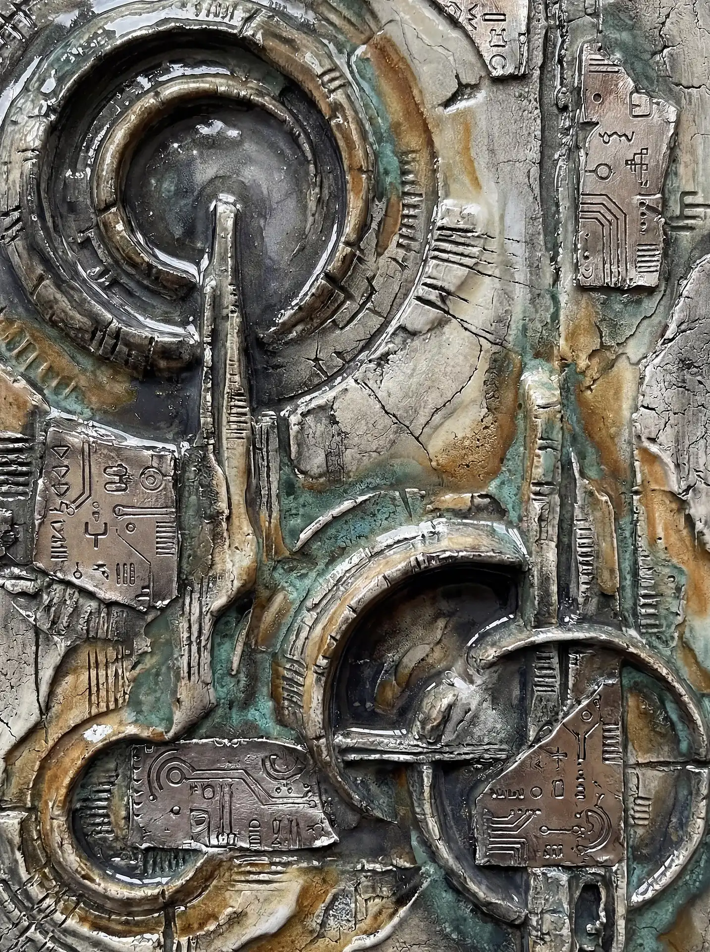 Metallic textures and weathered verdigris surfaces form a complex bas-relief composition reminiscent of ancient technology or futuristic circuit boards. The tactile artwork features intricate carvings and raised geometric shapes in shades of silver, bronze, and oxidized teal. Artwork by Constantine Cheshire